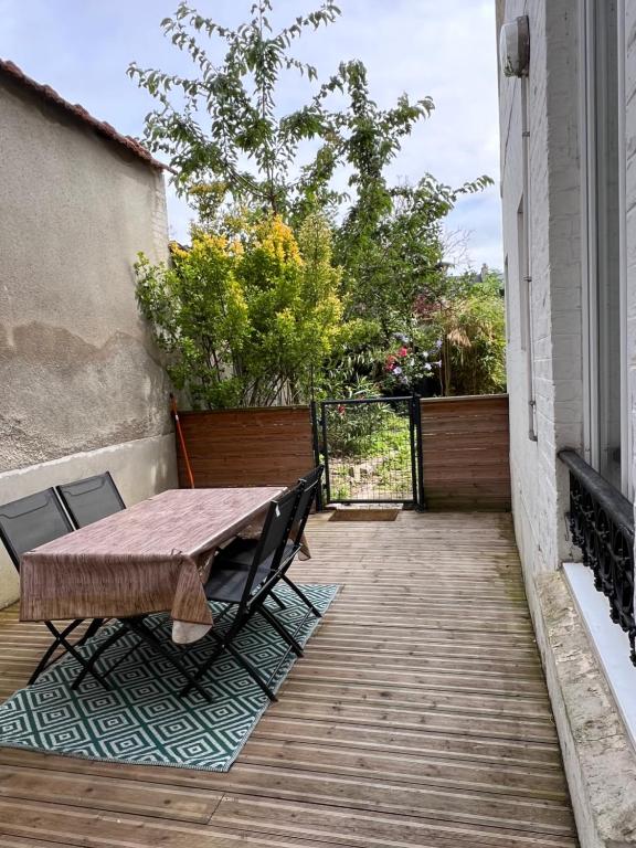 une terrasse en bois avec une table et des chaises dessus dans l'établissement Appartement hyper centre Reims Le gîte du sorcier, à Reims