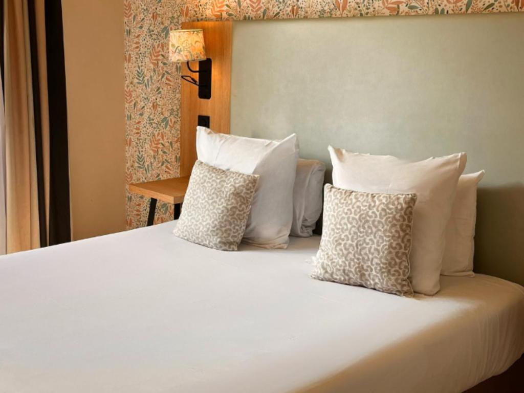 a white bed with white pillows on it at Séjours & Affaires Paris-Vitry in Vitry-sur-Seine
