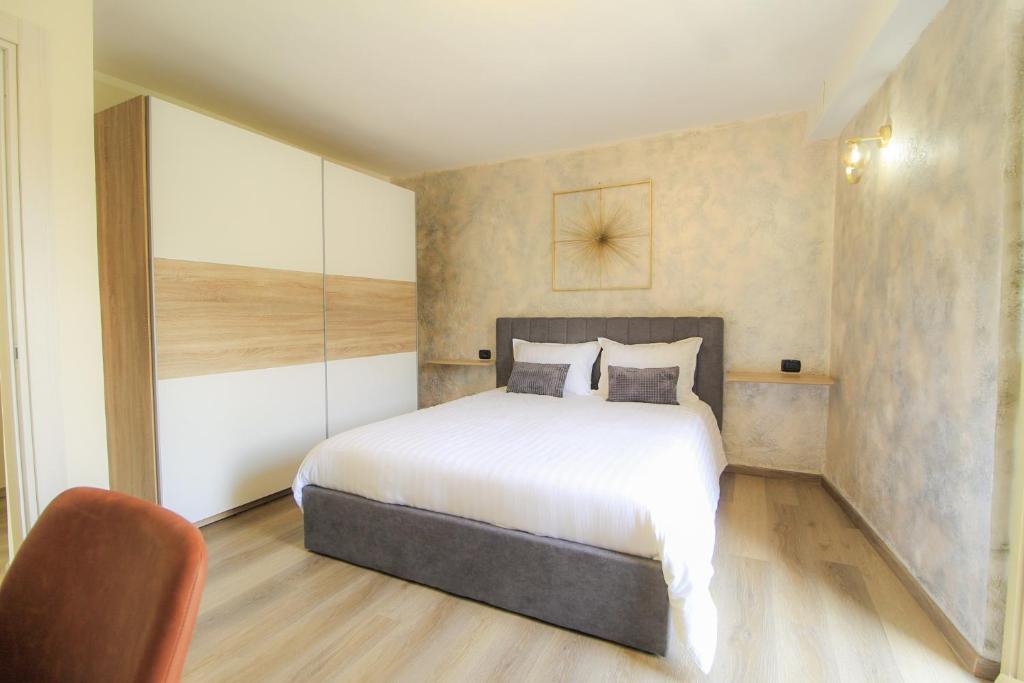Un dormitorio con una cama blanca y una silla. en Le camere del Cappello Verde, en Ivrea