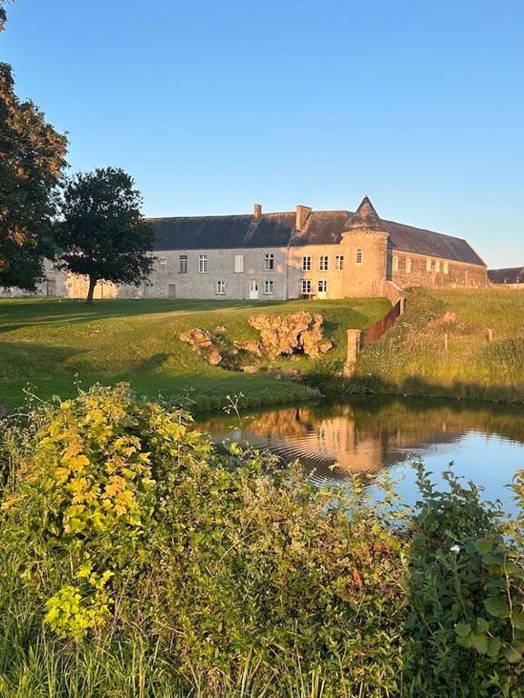 a building on a hill next to a body of water at CHÂTEAU DE FRANQUETOT & D Day Collins Museum in Sainte-Mère-Église