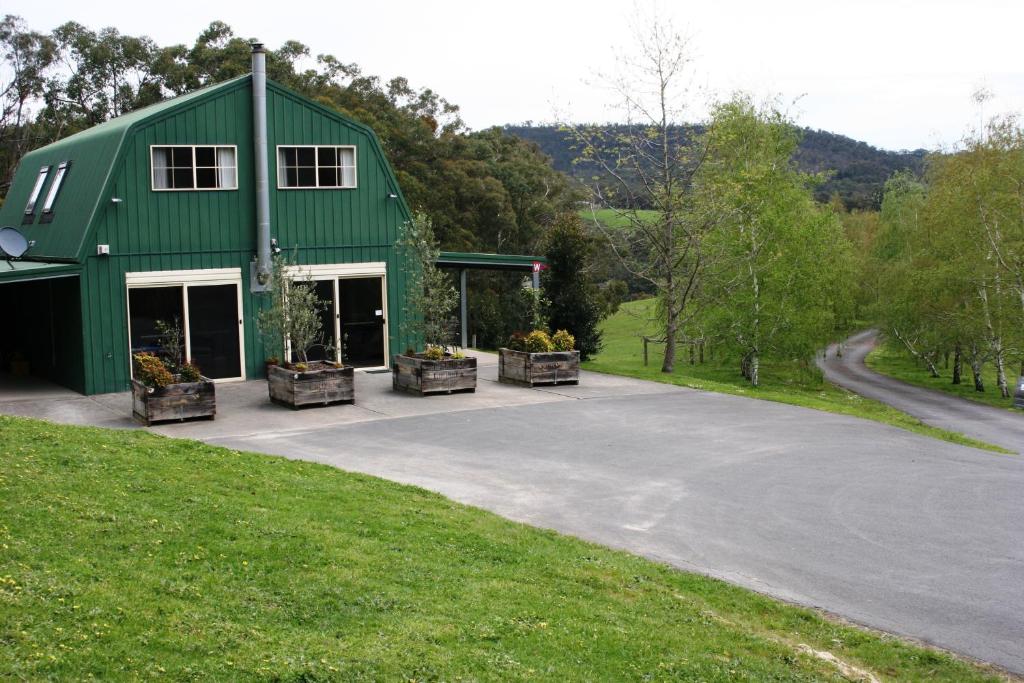 un edificio verde con un estacionamiento delante de él en The Barn at Charlottes Hill, en Healesville