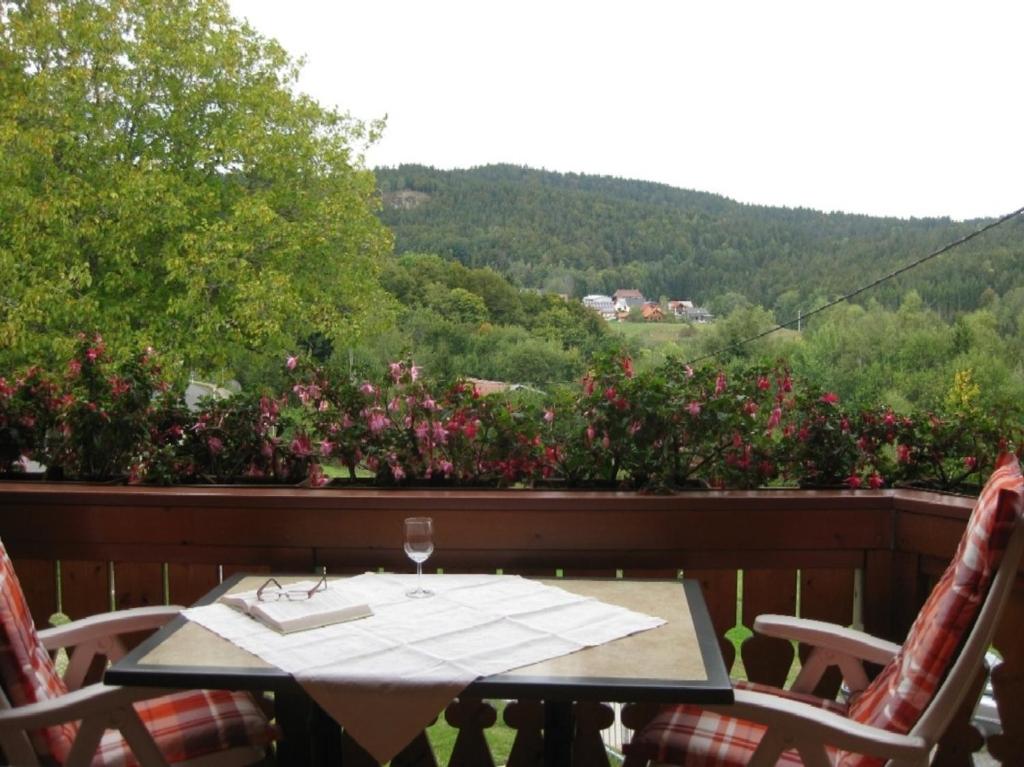 a table and chairs on a balcony with flowers at Fewo mit Balkon und herrlicher Fernsicht in Wittenschwand