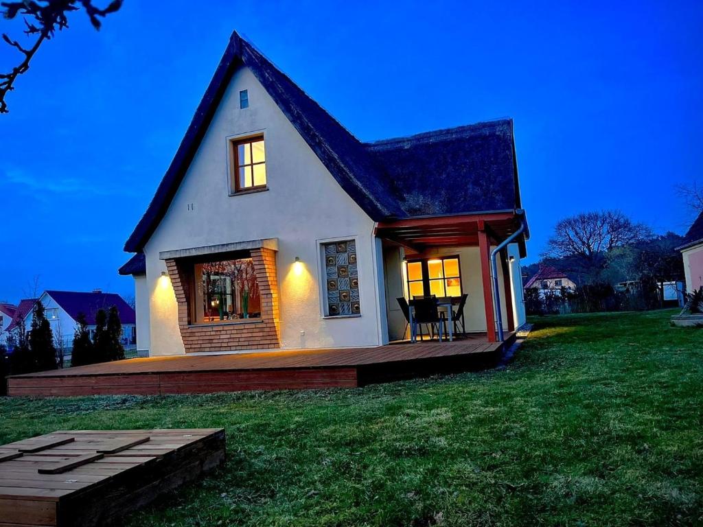 a white house with a black roof on a green field at HuusamDarß in Fuhlendorf