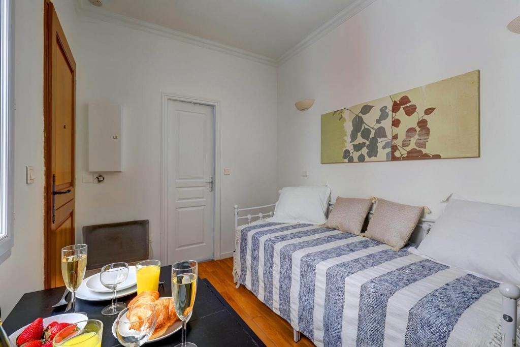 - une chambre avec un lit et une table avec de la nourriture dans l'établissement Bluestay 205 - Charmant Studio à Paris, à Paris