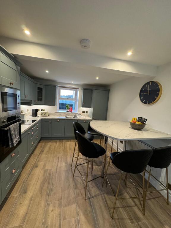 una cucina con tavolo, sedie e orologio di Krugers Guest House a Dunquin