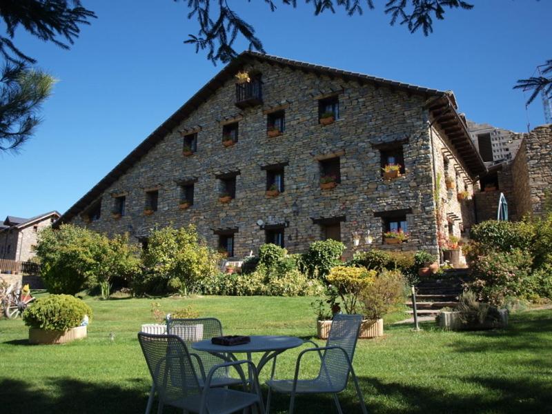 un bâtiment avec une table et des chaises devant lui dans l'établissement Casa Notario, à Asín de Broto