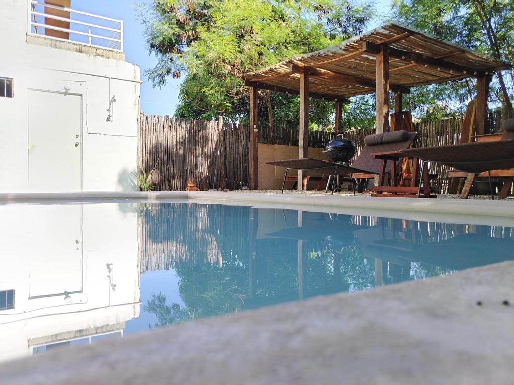 a swimming pool with a wooden gazebo and a picnic table at Luxury House Bacalar in Bacalar