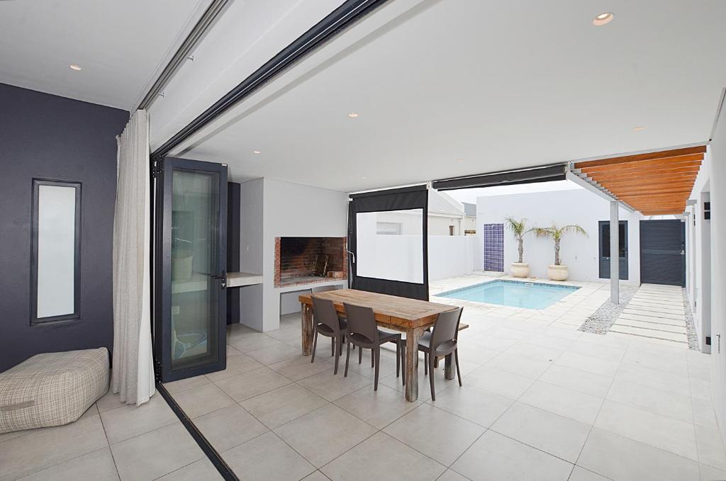 a dining room with a table and chairs and a pool at Above Board in Yzerfontein