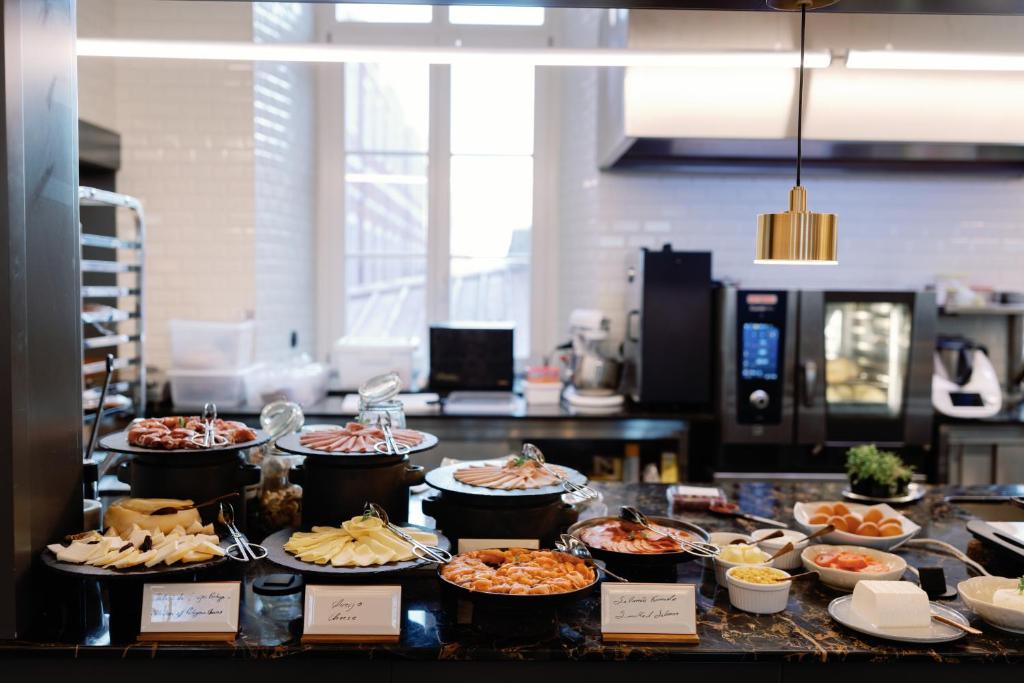 A breakfast buffet counter with labelled savoury dishes, seafood, cheeses and prepared accompaniments.