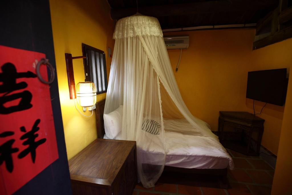 金沙鎮的住宿－山後48號（蕃茄紅了古厝民宿），一间卧室配有一张带蚊帐的床