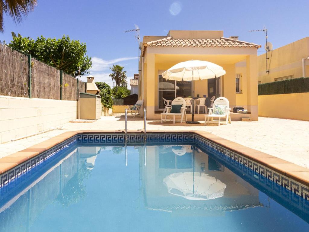 ein Swimmingpool mit Sonnenschirm neben einem Haus in der Unterkunft Holiday Home Flamenc 3 by Interhome in Riumar