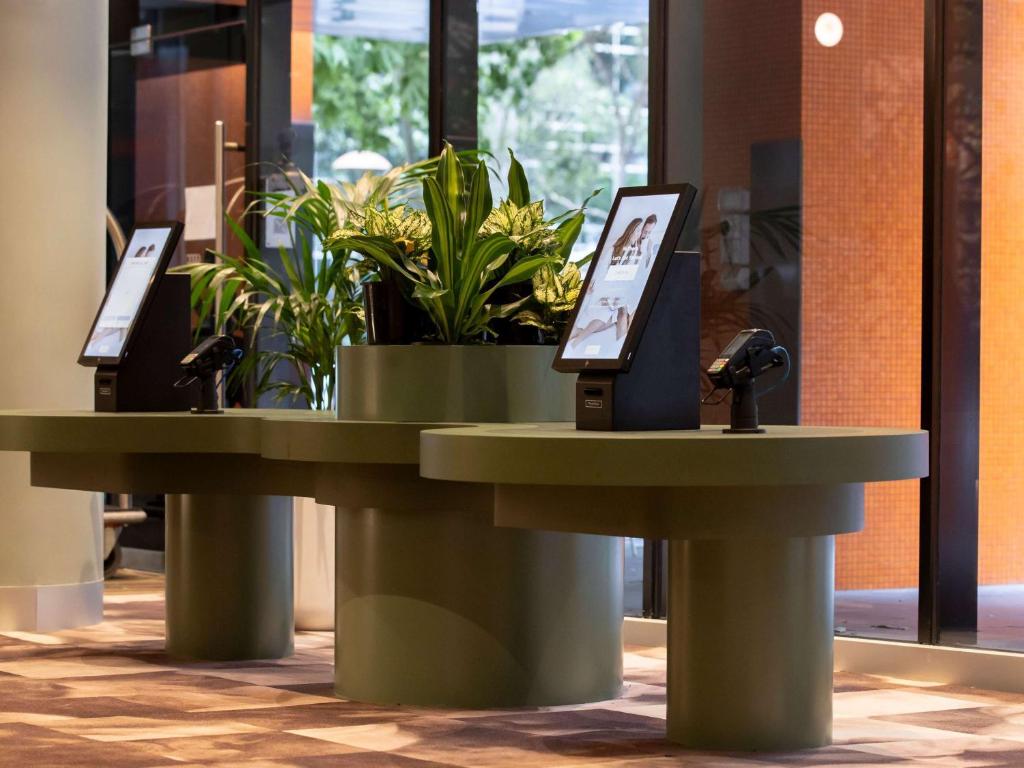 two tables with plants on them in a building at Mercure Melbourne Southbank in Melbourne