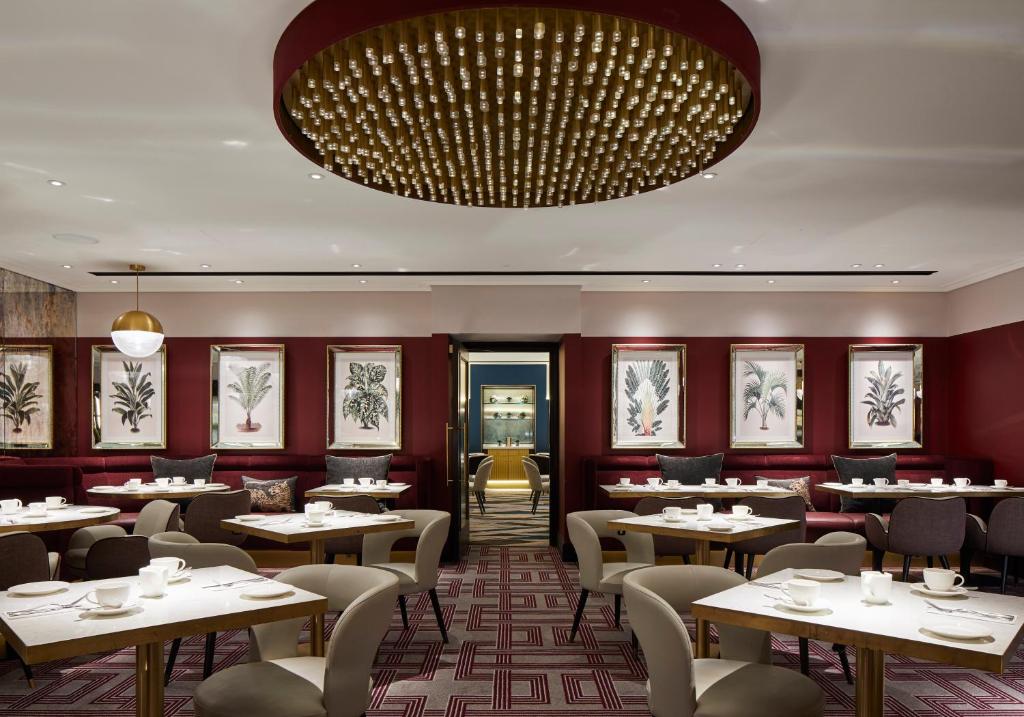 a restaurant with tables and chairs and a large chandelier at Strand Palace in London