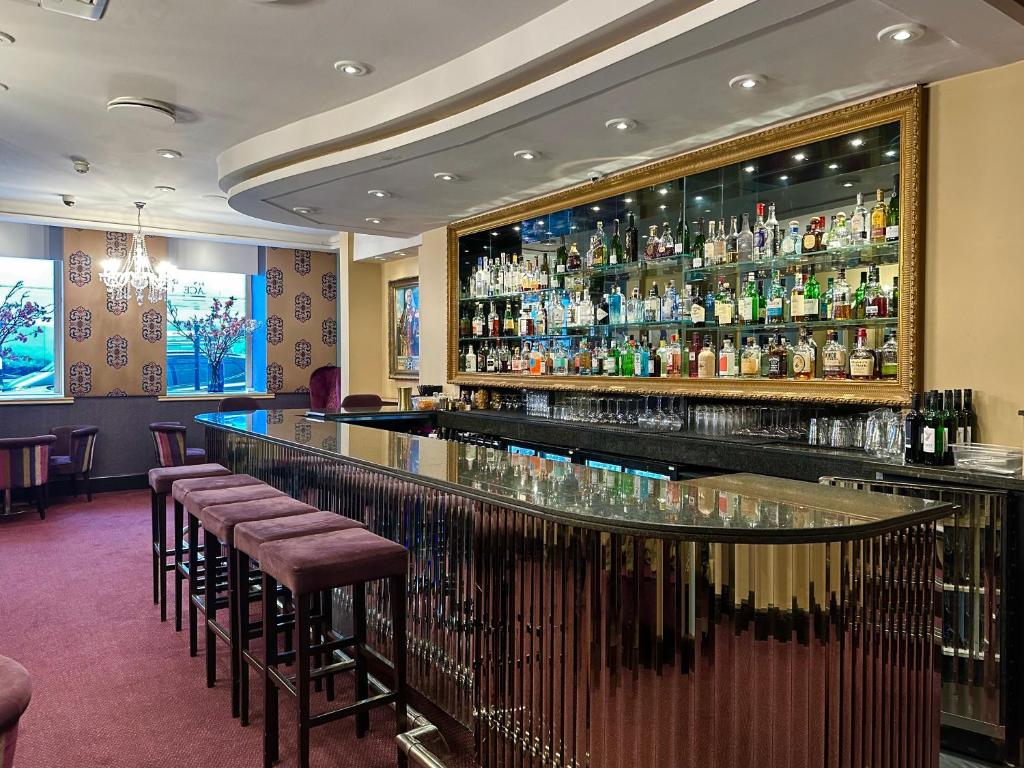 a bar in a restaurant with bar stools at Strand Palace in London
