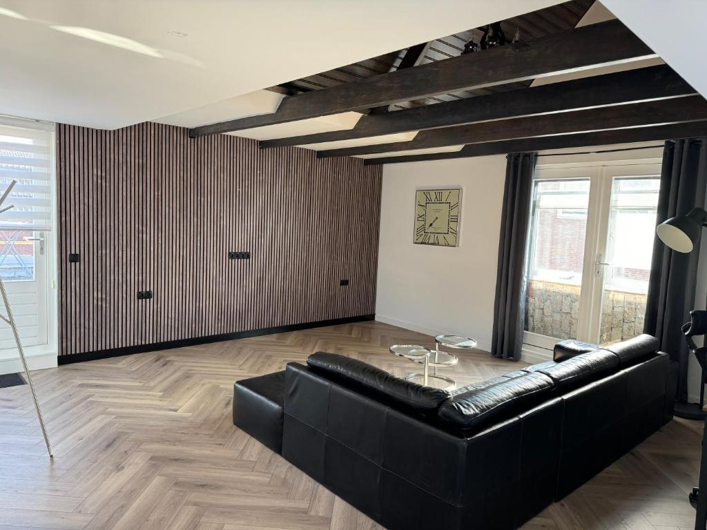 a living room with a black couch and a table at Smile home 2, Zaanse schans and Amsterdam Appartements in Wormerveer