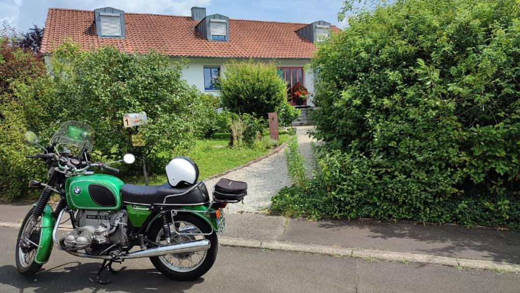 a green motorcycle parked in front of a house at Anette's nettes Dachjuchhe in Hofheim in Unterfranken
