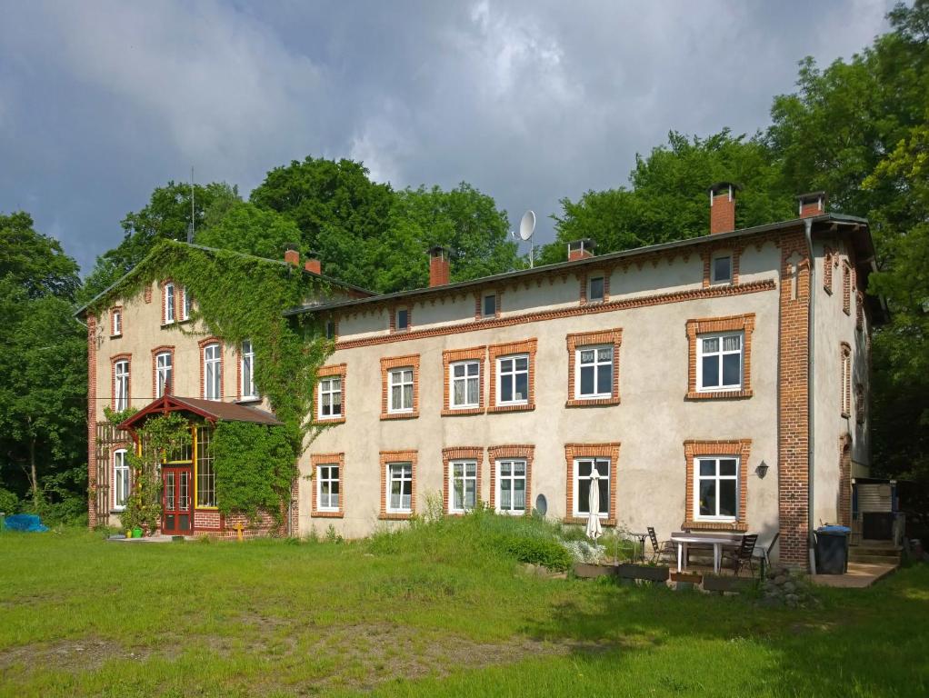 a large brick building in a grassy yard at Ferienwohnung und Gästezimmer im Gutshaus Alt-Krassow in Lalendorf
