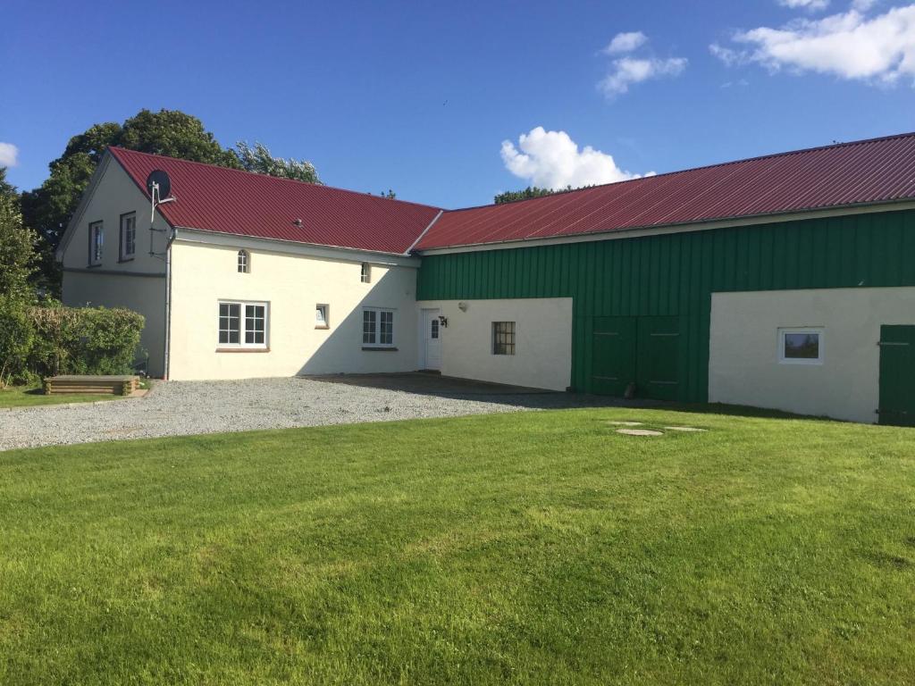 a large green and white building with a red roof at große Ferienwohnung Inselhuus in Nordstrand