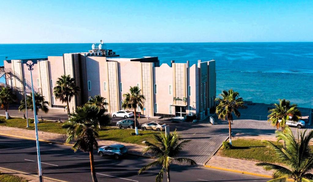 un gran edificio con palmeras frente al océano en نزل رالين للنزل السياحية, en Al Wajh