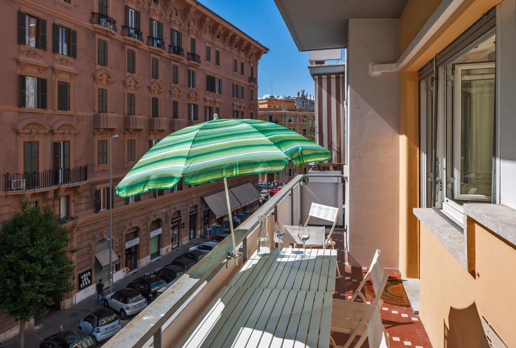 un balcón con una sombrilla verde y blanca en un edificio en Magenta Collection Fornaci, en Roma