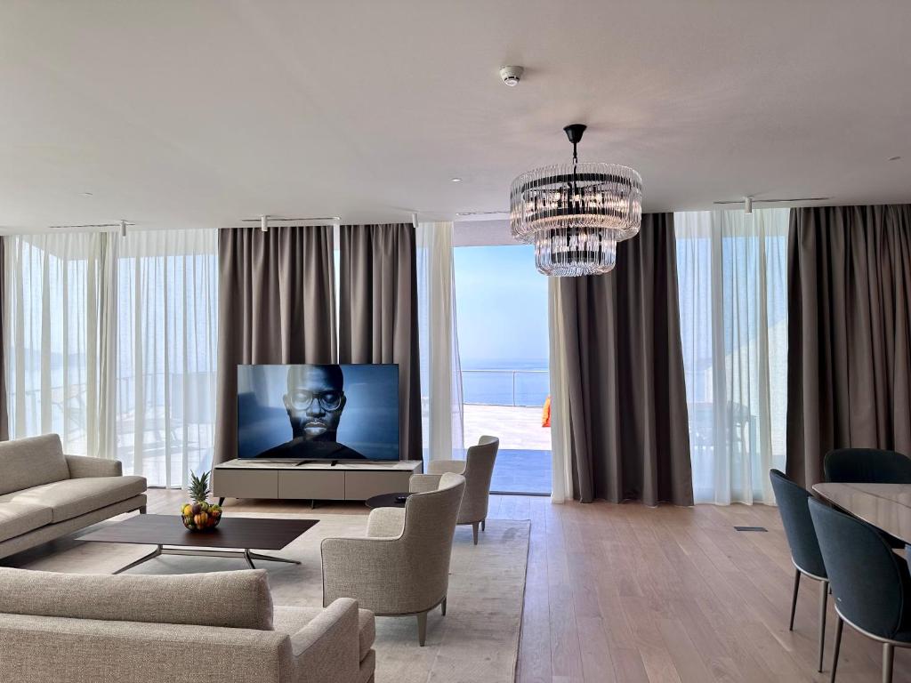a living room with a television and a couch and chairs at Sea Star Budva in Budva