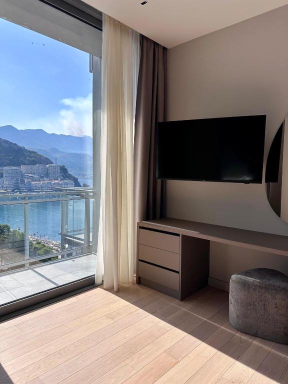 a living room with a large window with a television at Sea Star Budva in Budva