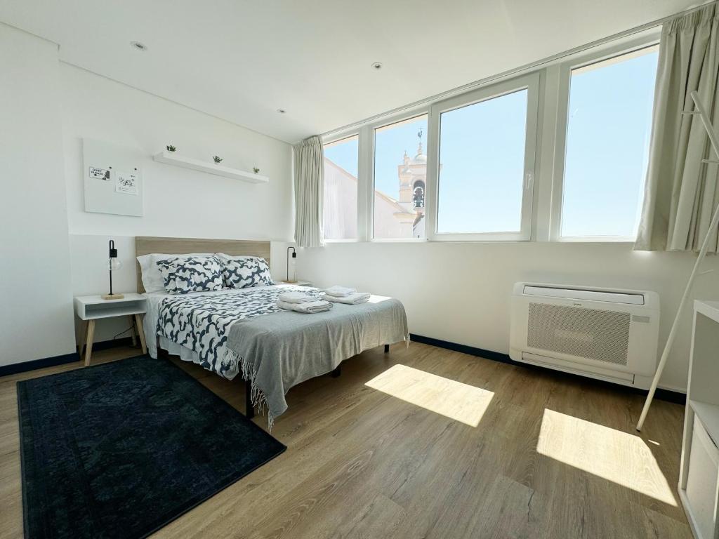 een slaapkamer met een bed in een kamer met ramen bij Guest House DML in Aveiro