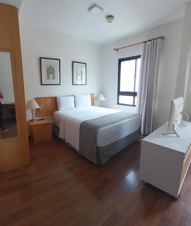 a bedroom with a large bed and a desk with a computer at Charmoso Flat em Pinheiros in Sao Paulo