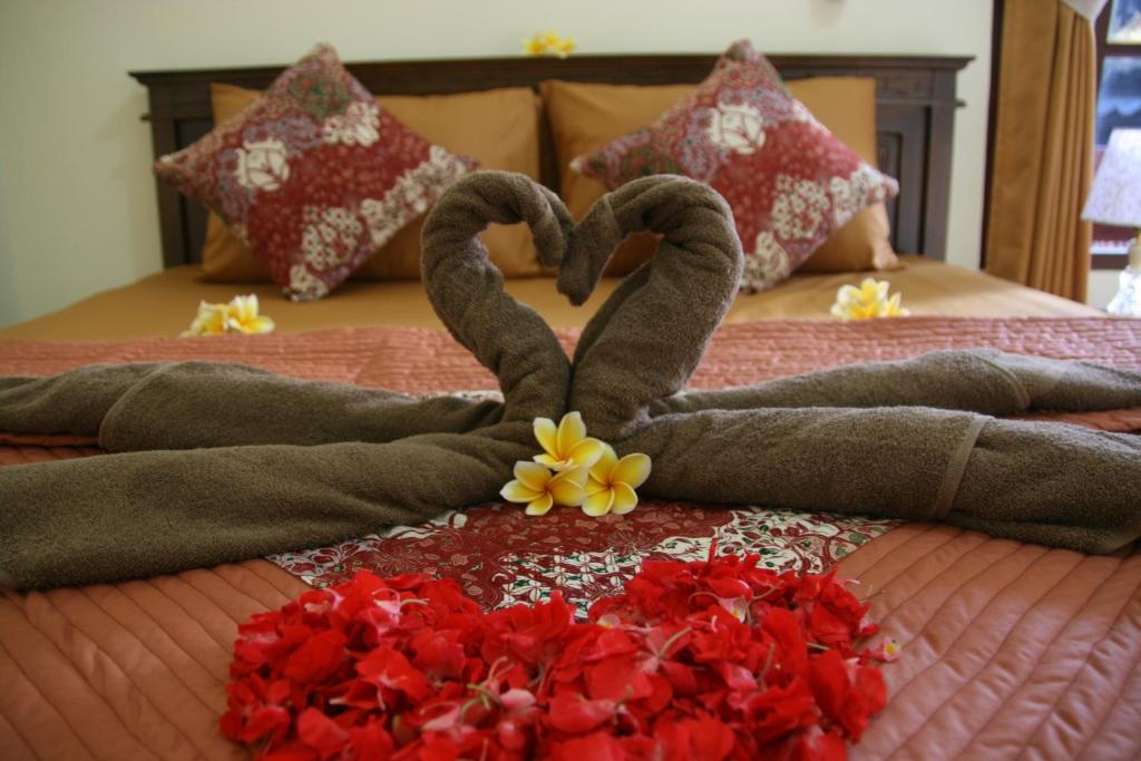 Una cama con dos cisnes hechos para parecer corazones en Santun Homestay en Ubud