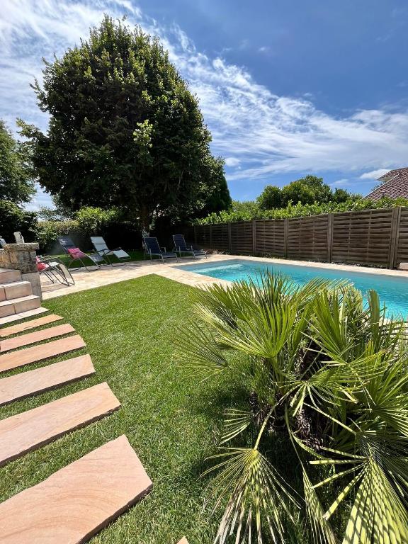 - une piscine avec un palmier dans la cour dans l'établissement Maison avec piscine à SEIGNOSSE 8 personnes, à Seignosse