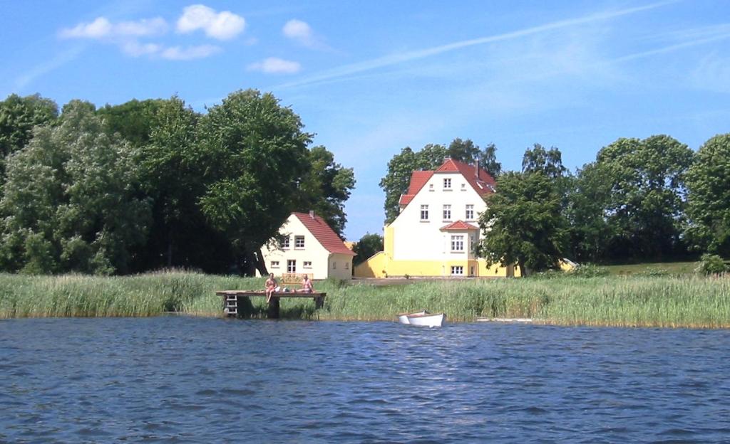 a boat on the water in front of two houses at Gut Grubnow in Grubnow