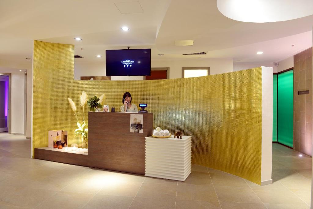 a woman standing at a counter in a lobby at Hotel Mirasole International in Gaeta