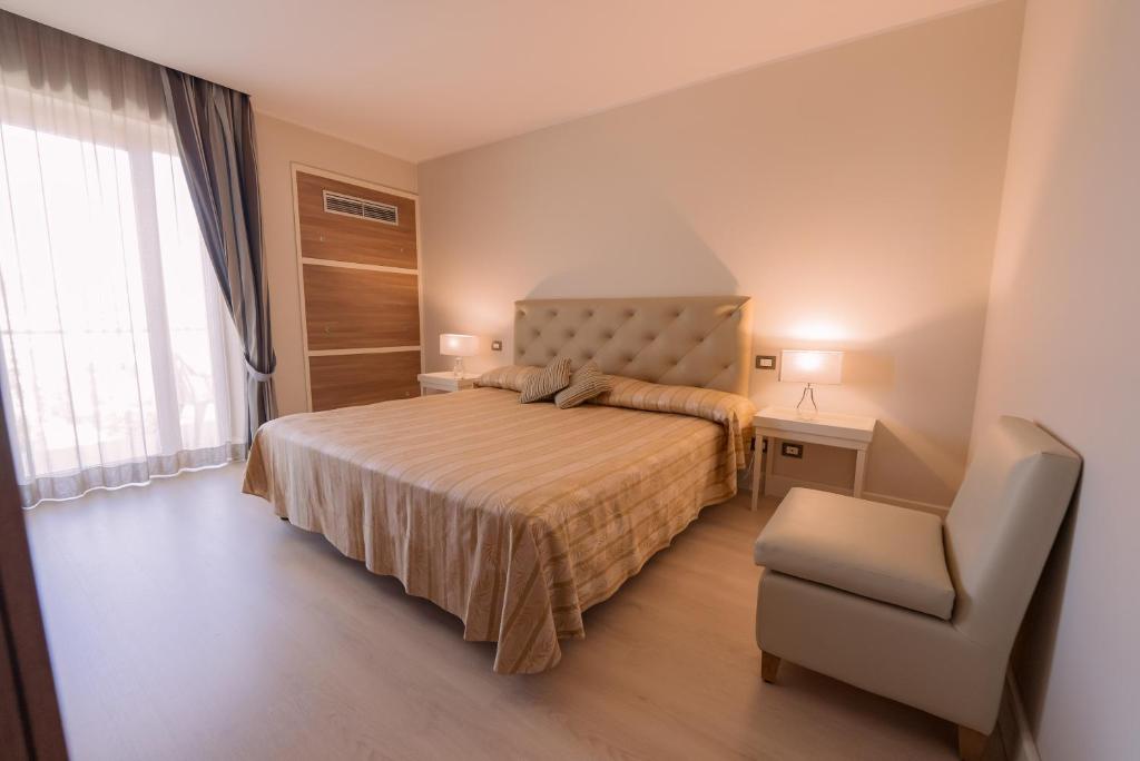 a bedroom with a bed and a chair and a window at Hotel Mirasole International in Gaeta