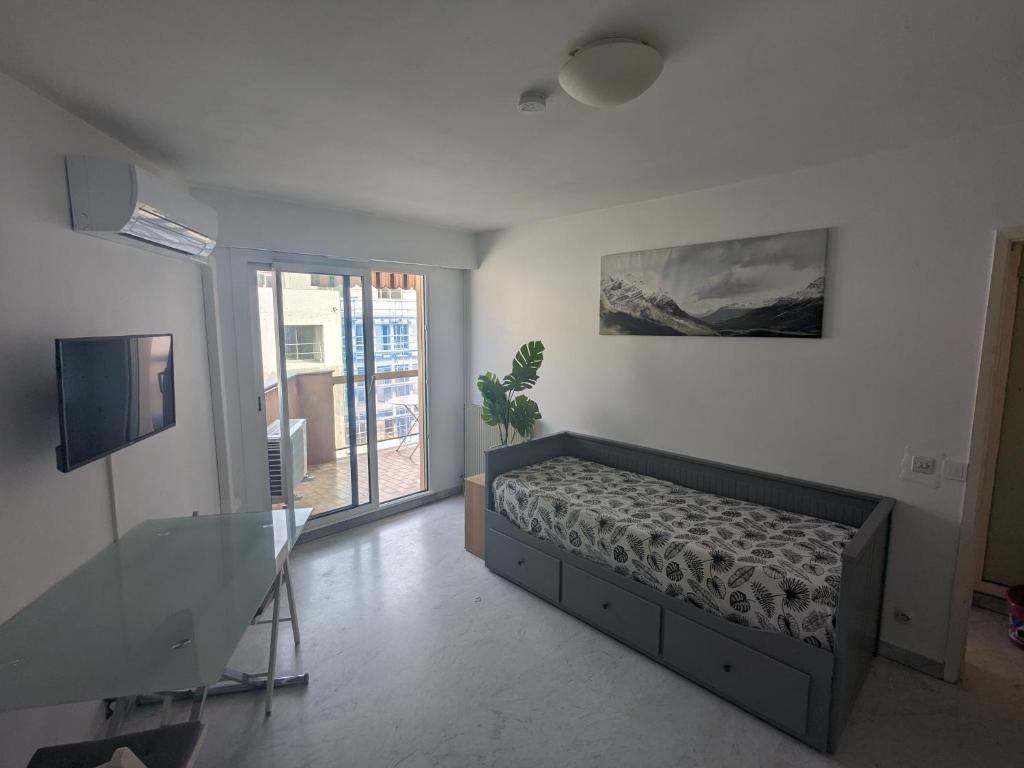 Un dormitorio con una cama y un televisor y una ventana. en Vue dégagée, emplacement idéal, climatisé, en Menton