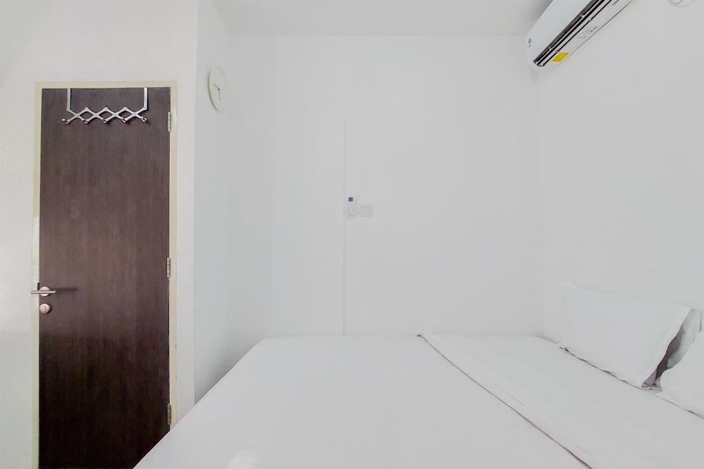 a room with a brown door and a white wall at Comfort and Cozy Style 1BR at Serpong Garden Apartment By Travelio in Tangerang