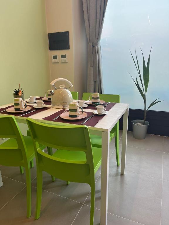 a dining room table with green chairs and a table with cups at Al Ventisei - Verde in Treiso