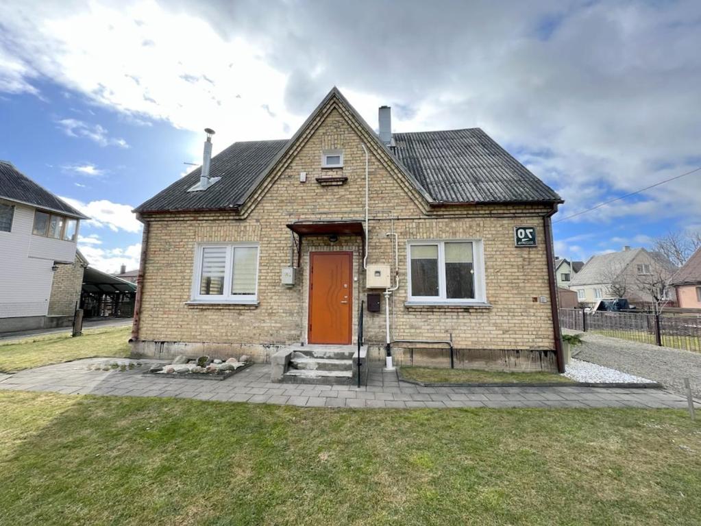 een stenen huis met een rode deur op een erf bij Vintage 70 Villa in Šiauliai