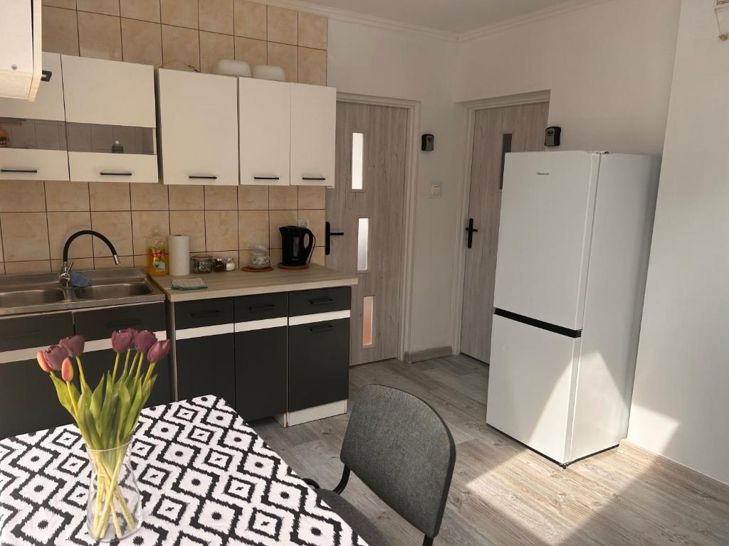 a kitchen with a table and a white refrigerator at "ToTU!" ŚCISŁE CENTRUM Wi-Fi & NETFLIX W KAZDYM POKOJU, Pokoj 1-osobowy in Hrubieszów