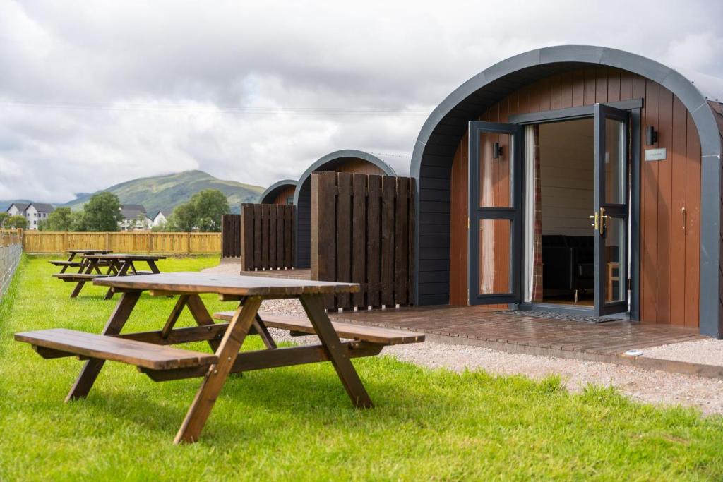 a picnic table and benches in front of a building at Ben Nevis Pod in Fort William