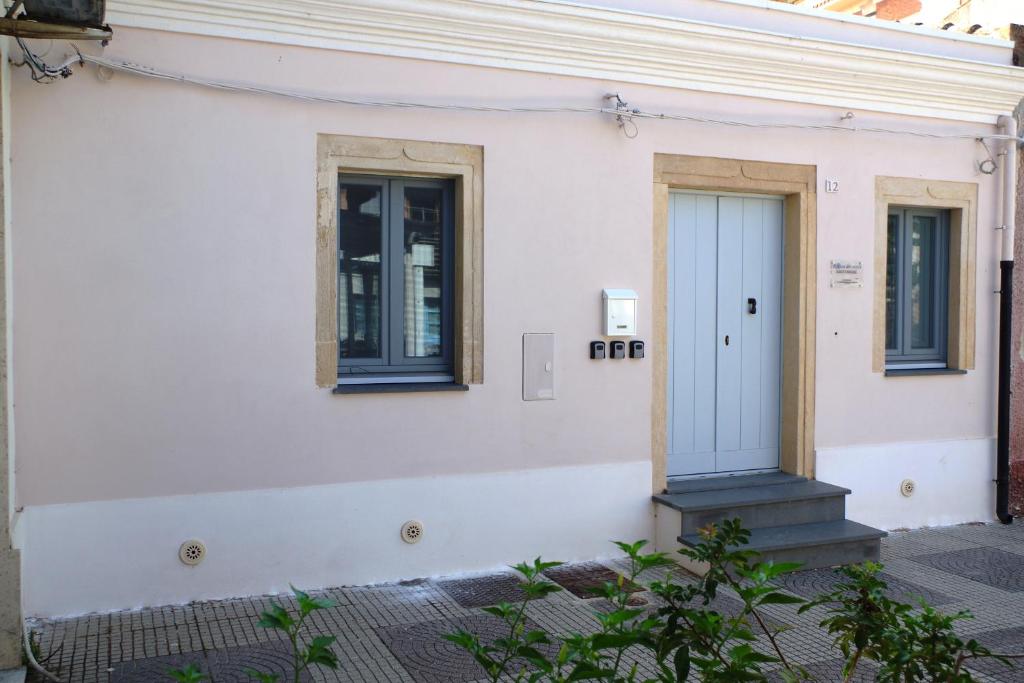 Casa blanca con puerta azul y 2 ventanas en Rosa Dei Venti Guest House, en Cabras