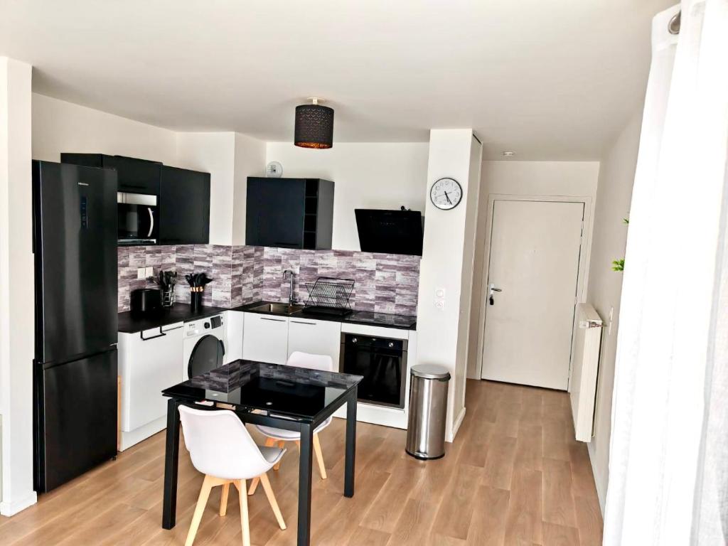a kitchen with a table and a black refrigerator at Cosy 2 pièces proche aéroport in Villepinte