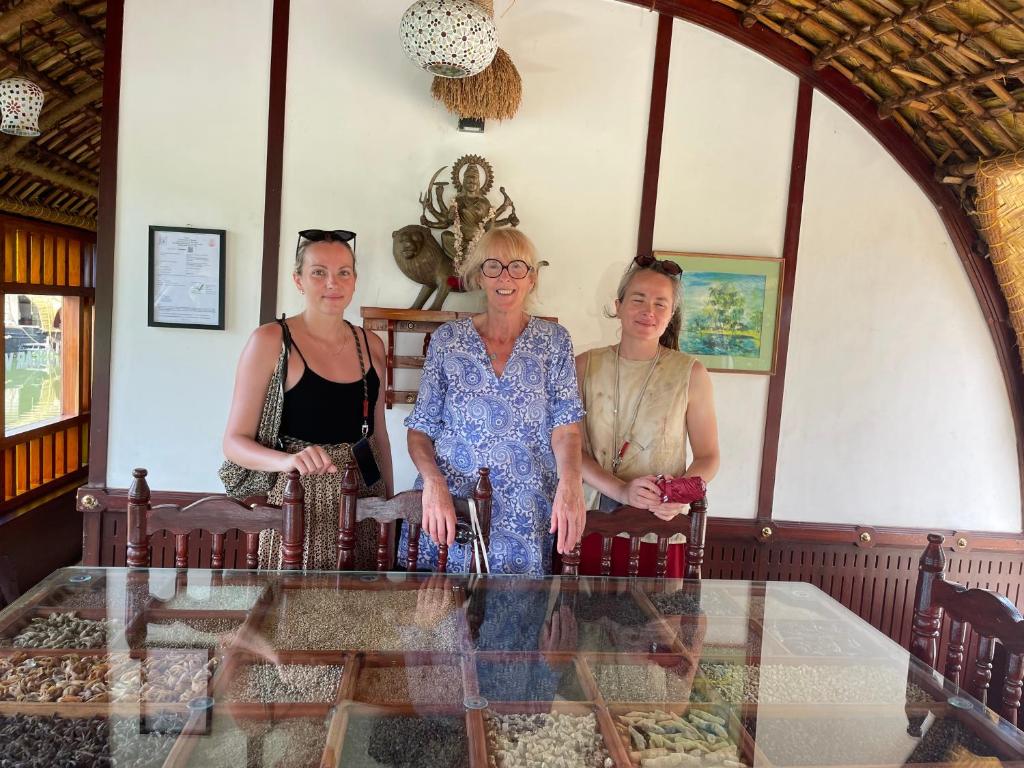 a group of three women standing around a glass table at Thara's Houseboat in Alleppey