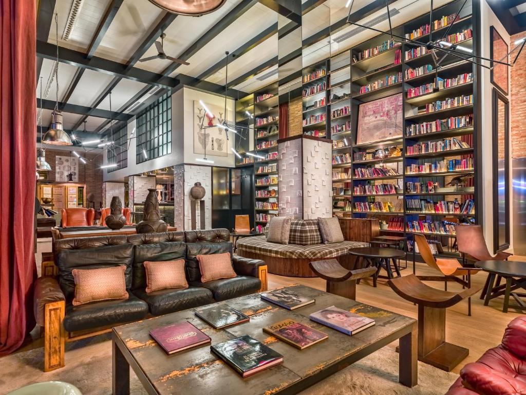 a library with a couch and tables and bookshelves at H10 Tribeca in Madrid