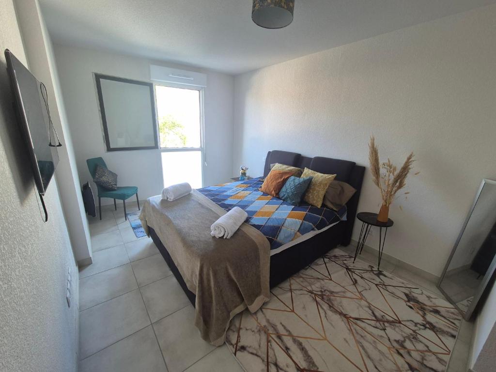a bedroom with a bed with a blanket and a window at Appartement bella vista marseillan in Marseillan