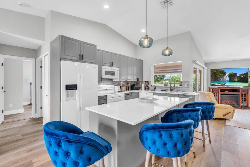 une cuisine avec un comptoir blanc et des chaises bleues dans l'établissement 4 Miles to Beach and Walk to Shops, à Naples