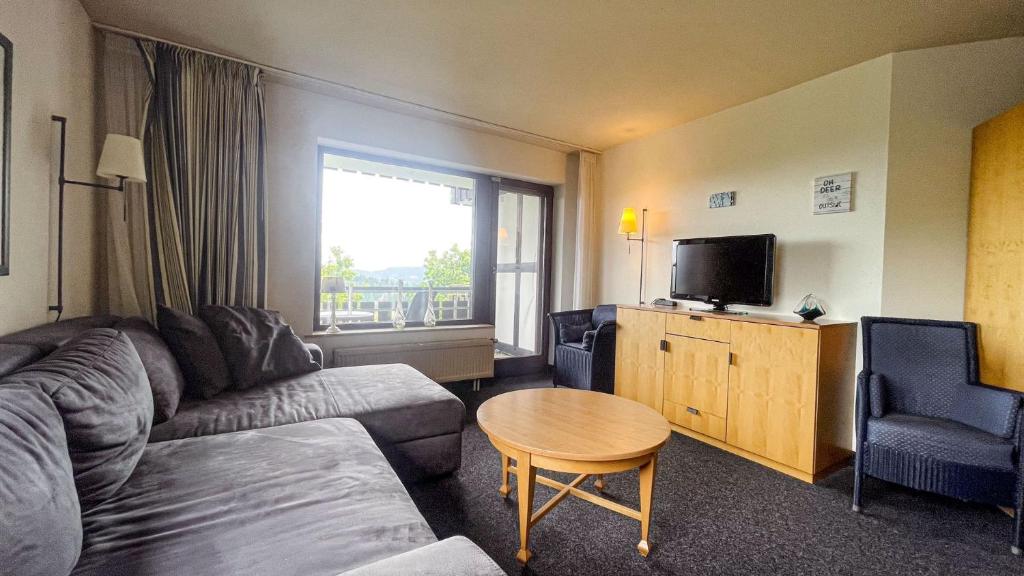 ein Wohnzimmer mit einer Couch, einem Tisch und einem Fernseher in der Unterkunft FeWo 238 in Winterberg