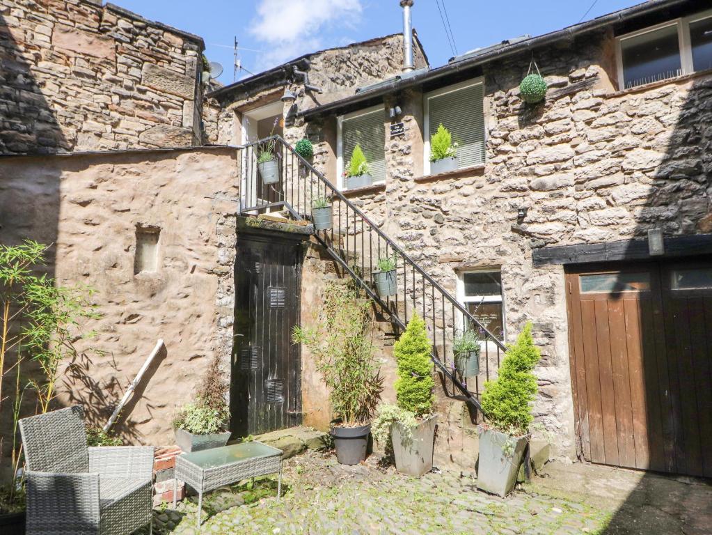 une maison en pierre avec une porte en bois et des plantes en pot dans l'établissement The Landings, à Kirkby Lonsdale