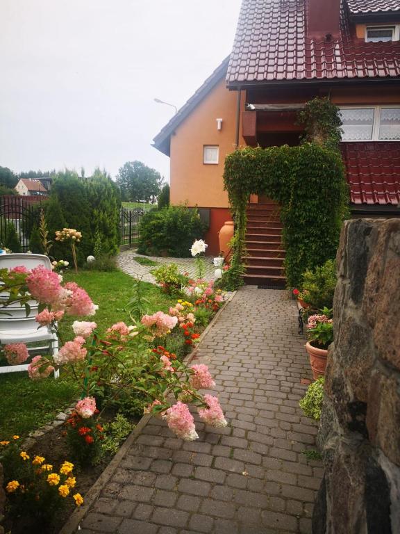 a house with a brick walkway with flowers in front of it at Apartament 2pokojowy 4-5osobowy in Węgorzewo