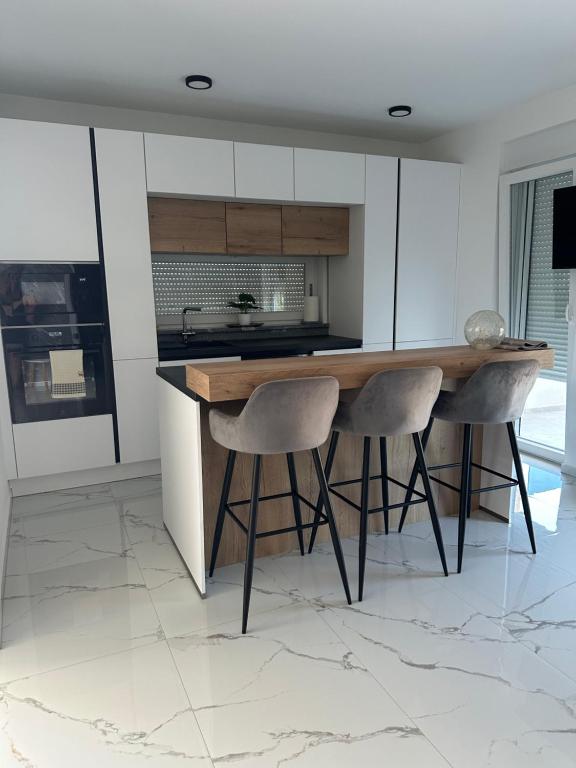 a kitchen with a counter and two stools at Apartments Albatross in Novalja