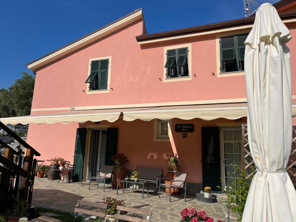 a pink house with a white umbrella and a patio at L'antico Frantoio dei nonni in Sestri Levante